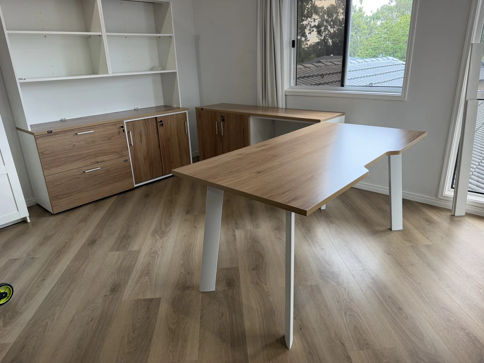 Wood-finish desk beside matching shelving